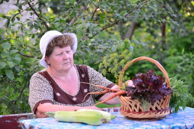 yaşlı kadın ile masada oturan sebze sepeti