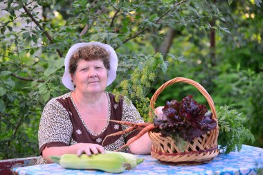 yaşlı kadın ile masada oturan sebze sepeti
