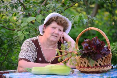 yaşlı kadın ile masada oturan sebze sepeti