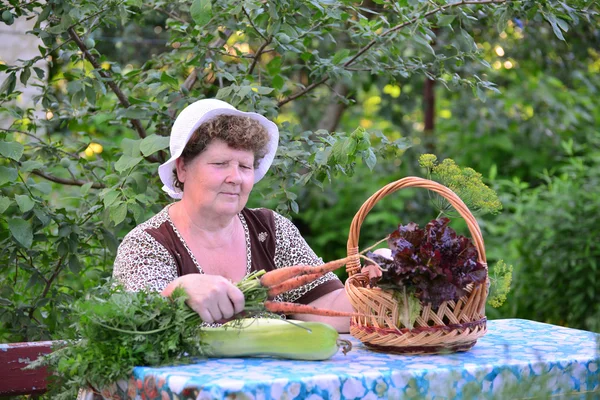 Ältere Frau mit Gemüsekorb sitzt am Tisch — Stockfoto