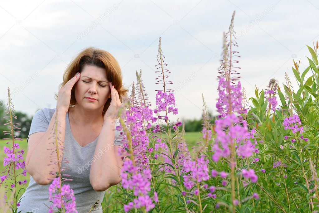Portrait of  woman with headache near willow-herb in the field