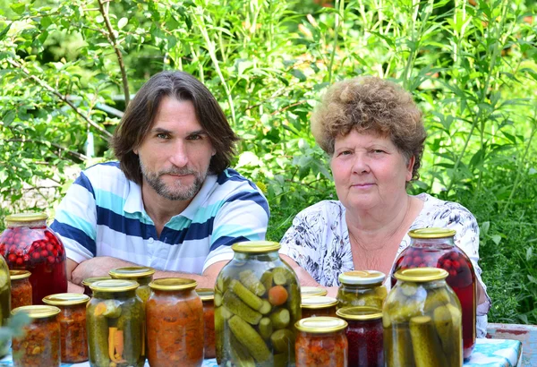 Женщина и ее сын за столом с консервированными овощами — стоковое фото