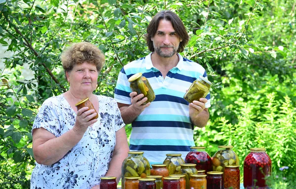 Kadın ve oğlu ile masada sebze konserveler — Stok fotoğraf