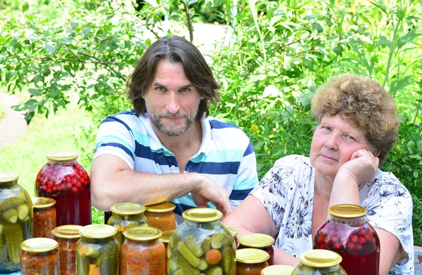 Жінка і її син за столом з консервованими овочами — стокове фото