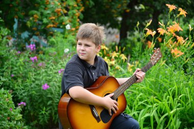 Genç çocuk bir yaz aylarında açık gitar çalmak