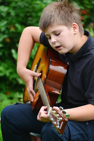 Teen boy playing guitar outdoor in a summer — Stock Photo, Image