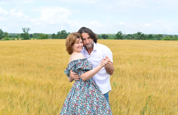 Loving middle-aged couple standing in field in summer — Stock Photo, Image