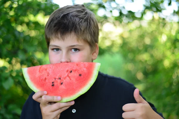 Tiener jongen watermeloen eten in de natuur — Stockfoto