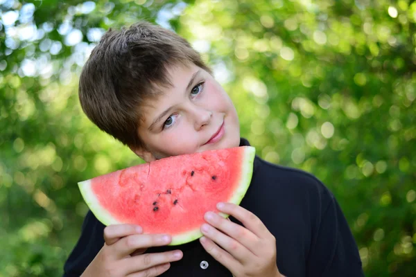 Tiener jongen watermeloen eten in de natuur — Stockfoto