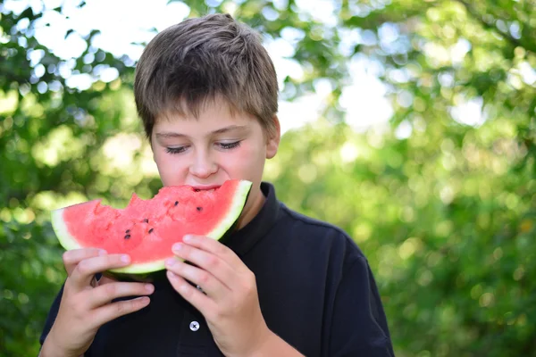 Teen boy eating watermelon in nature — Stock Photo, Image