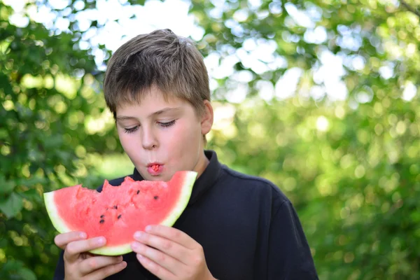 Teen boy eating watermelon in nature — Stock Photo, Image