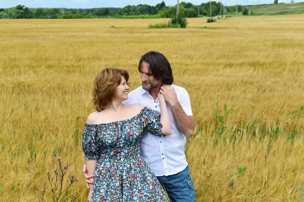 Loving middle-aged couple standing in field in summer — Stock Photo, Image