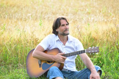 Bir adam bir alanda bir gitar ile