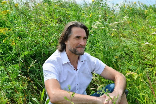 Man sits in the tall grass in  summer — Stock Photo, Image