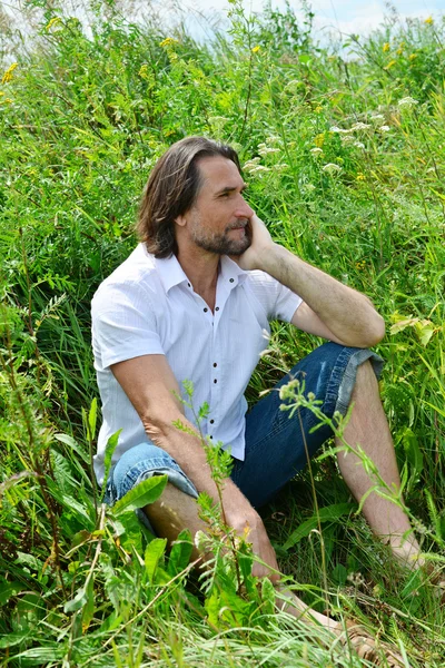 男が夏に背の高い草に座ってください。 — ストック写真