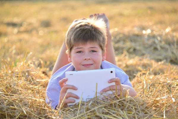 Ragazzo adolescente che gioca su un tablet sul campo — Foto Stock