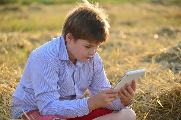 Jongen tiener spelen op een tablet in het veld — Stockfoto