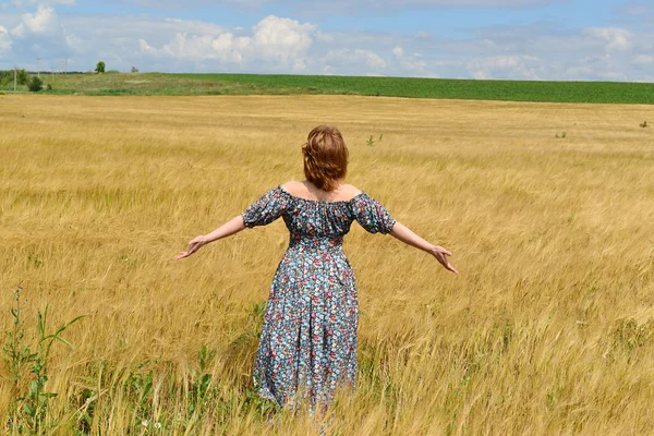 Kobieta w maxi sukienka stojący na polu żyta — Zdjęcie stockowe