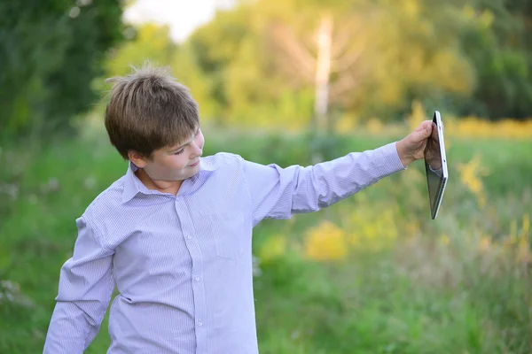 Adolescente chico con tableta ordenador en la naturaleza — Foto de Stock