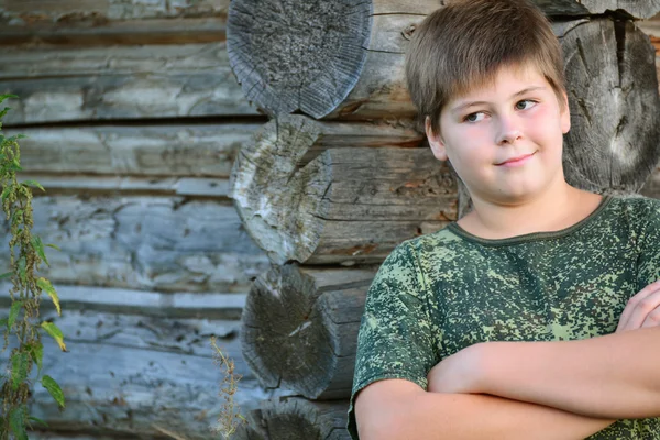 Teen pojke i kamouflage står nära trävägg — Stockfoto