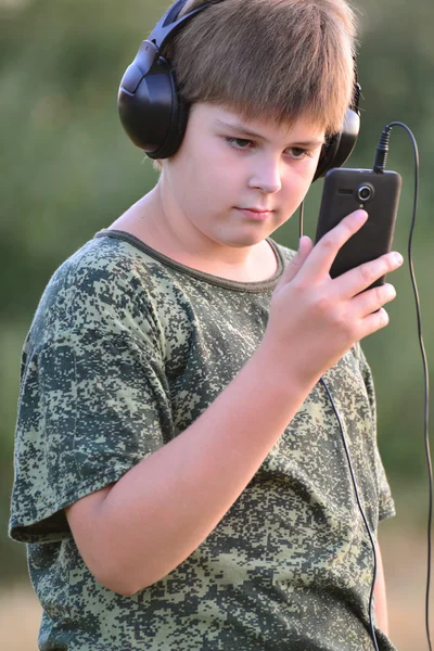 Niño escuchando música en auriculares con smartphone — Foto de Stock