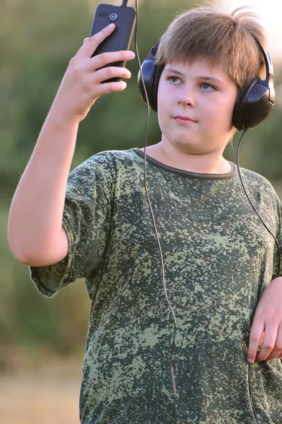 Pojke lyssna på musik i hörlurar med smartphone — Stockfoto