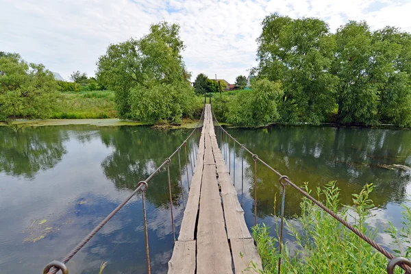 Hanging pedestrian bridge across the river — Stock Photo, Image