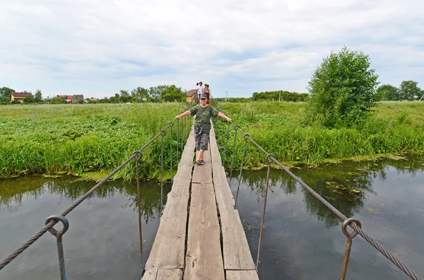 People walk on  suspension bridge over the river — Stock Photo, Image