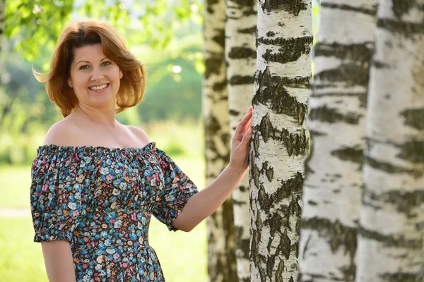 Frau im Kleid mit offenen Schultern geht es um Birke — Stockfoto