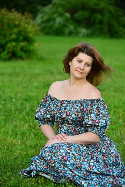 Femme dans une robe avec les épaules ouvertes assis sur l'herbe — Photo