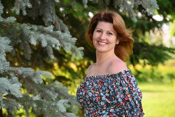 Femme dans une robe aux épaules ouvertes à la forêt de pins — Photo