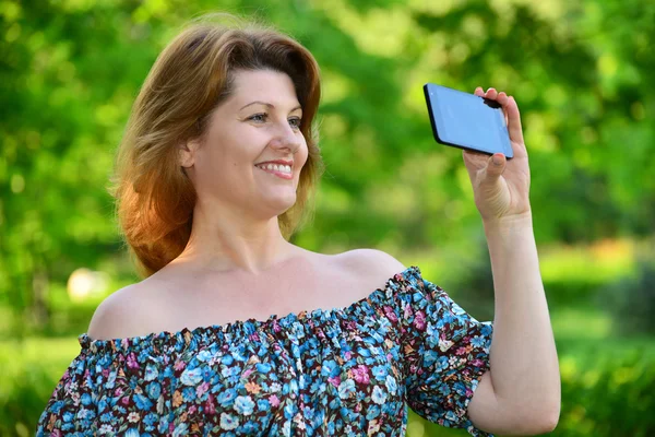 Жінка з мобільним телефоном у сосновому парку — стокове фото