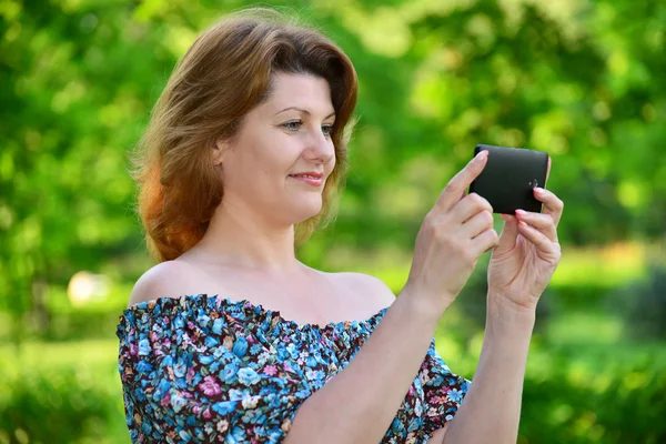 Donna con un telefono cellulare nel parco dei pini — Foto Stock