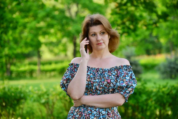 Donna con un telefono cellulare in natura in estate — Foto Stock