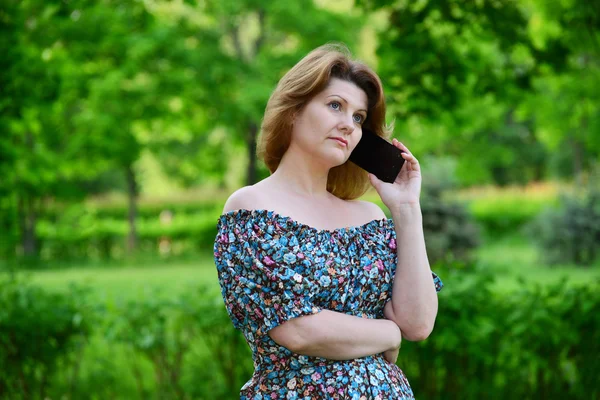 Donna con un telefono cellulare in natura in estate — Foto Stock