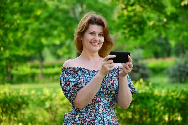 Жінка з мобільним телефоном у природі влітку — стокове фото