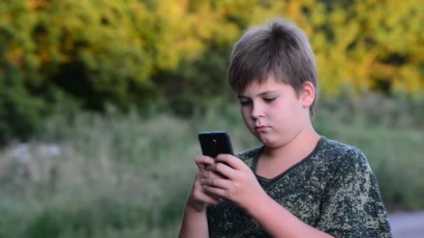 Adolescent garçon utilise smartphone à l 'air libre — Video