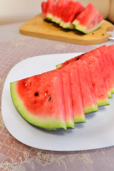 Skivor av vattenmelon på en tallrik vid bordet — Stockfoto