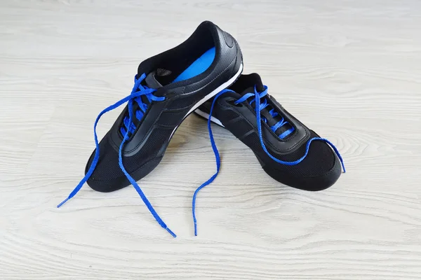 Кросівки з блакитними шнурками на підлозі — стокове фото