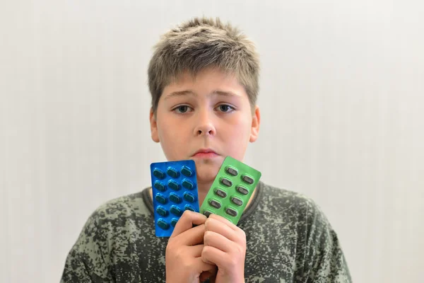 Boy in camouflage shirt holding a drugs — Stock Photo, Image