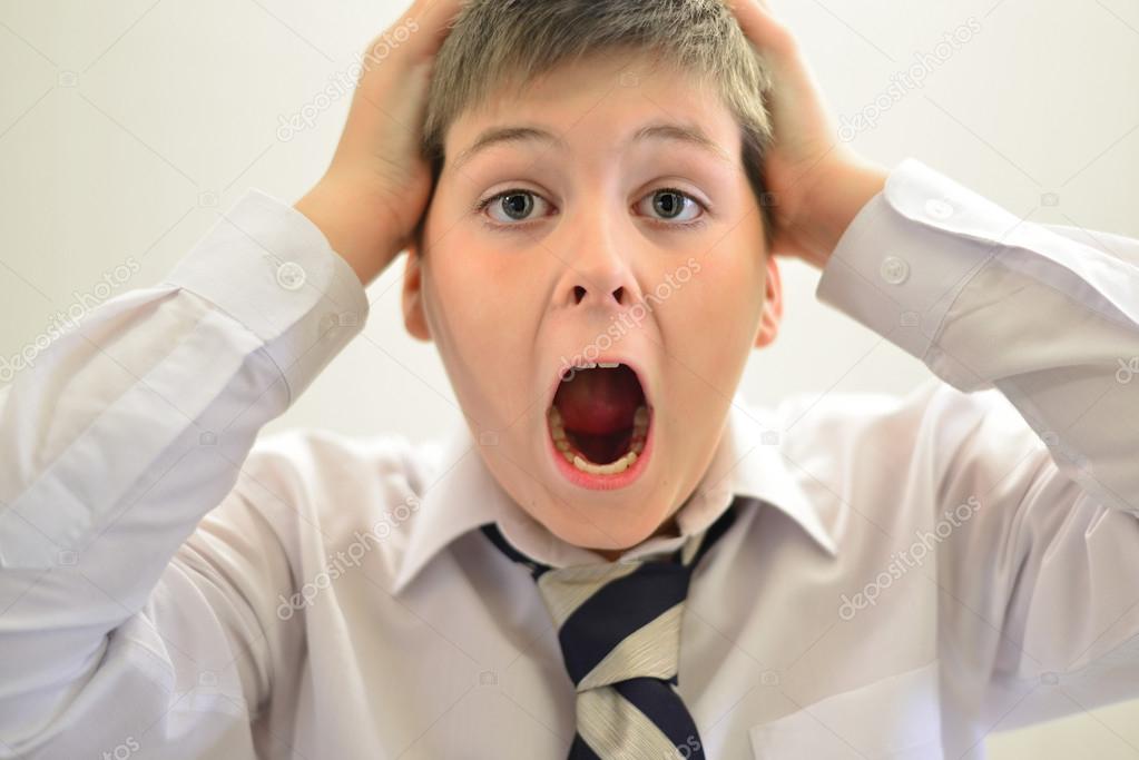Teen boy screaming holding his hands behind  head