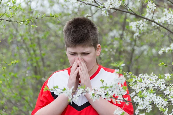 Chłopiec z alergicznym nieżytem nosa w wiosenny ogród — Zdjęcie stockowe