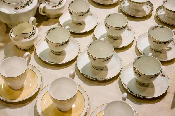 Birçok çay bardak ve tabaklar masanın üzerine vardır — Stok fotoğraf