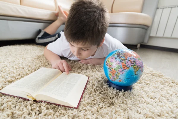 研究地球仪和看书的男孩 — 图库照片