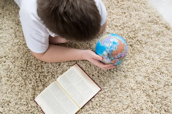 研究地球仪和看书的男孩 — 图库照片