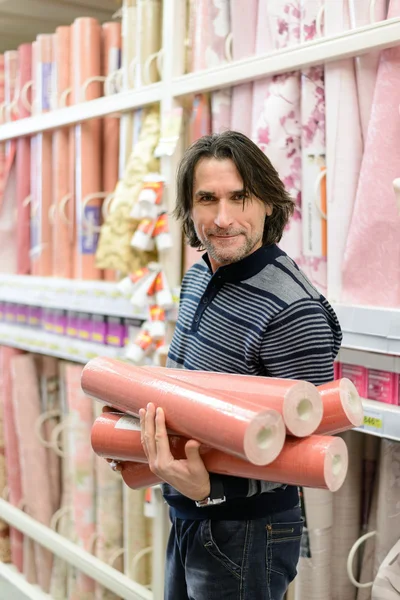 Человек держит рулон обоев в магазине — стоковое фото