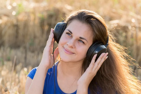 Menina ouvindo música no campo — Fotografia de Stock