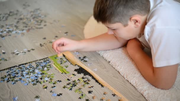 Teenager boy collects puzzles  lying on  floor — Stock Video