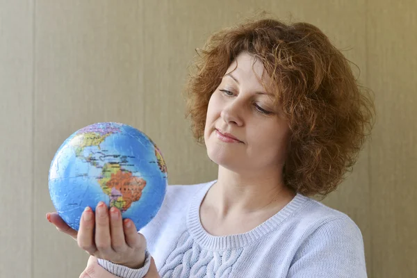 Globe kezében gondolkodó utazó nő — Stock Fotó
