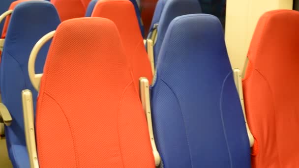 Interieur van een lege trein met rode en blauwe zitplaatsen — Stockvideo